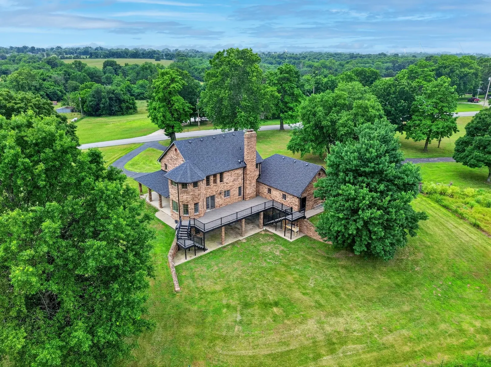 Aerial view of a brick home surrounded by trees and acreage