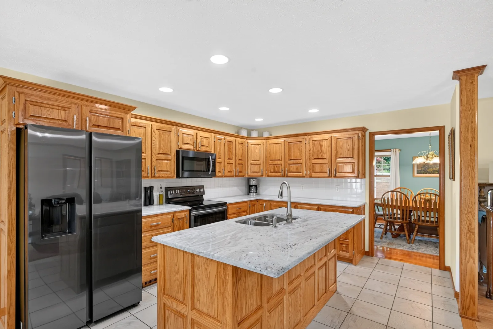 Kitchen with oak cabinets, a granite island and a view into the dining room