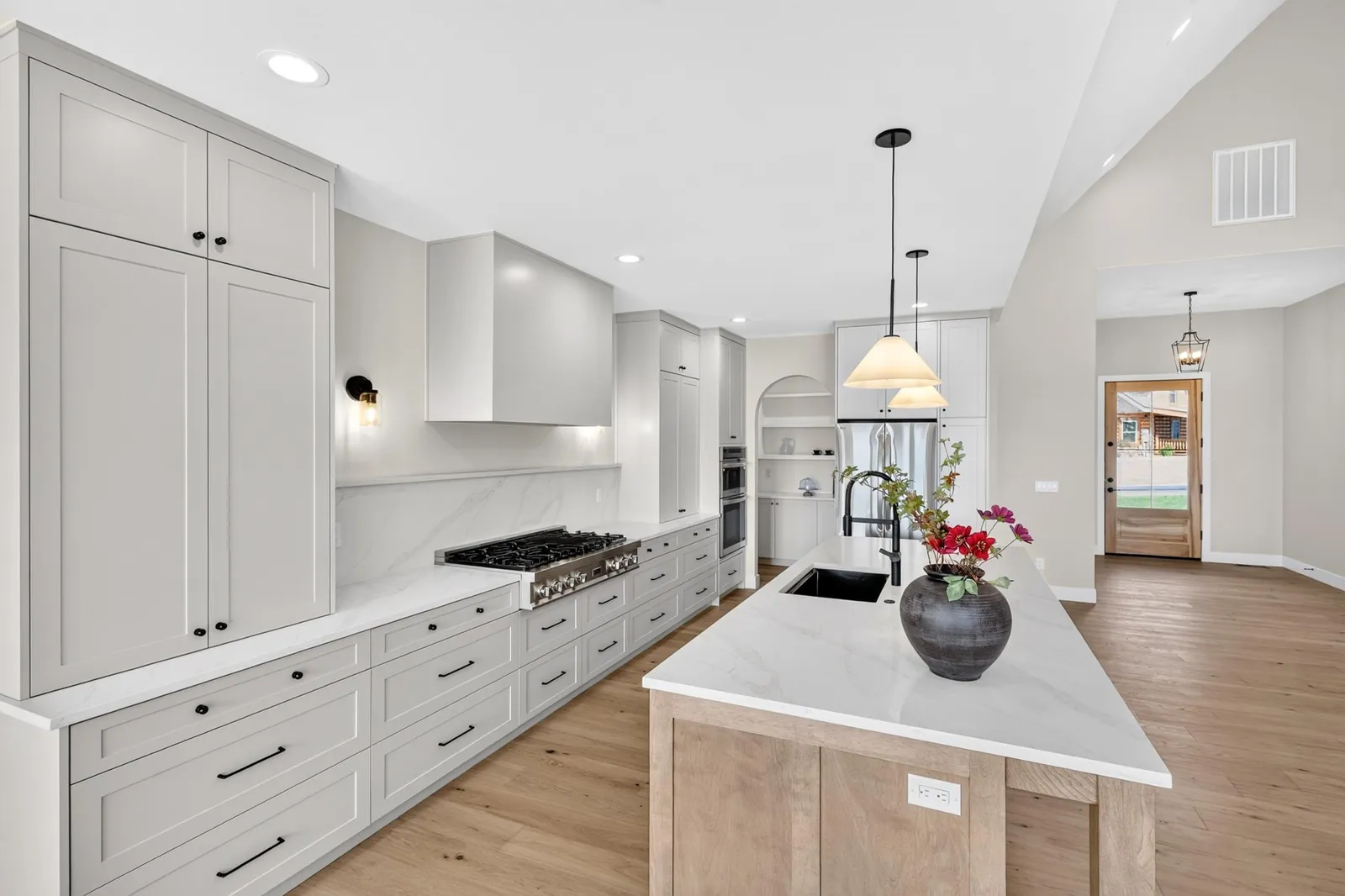 White kitchen with a large island, pendant lights and a professional range