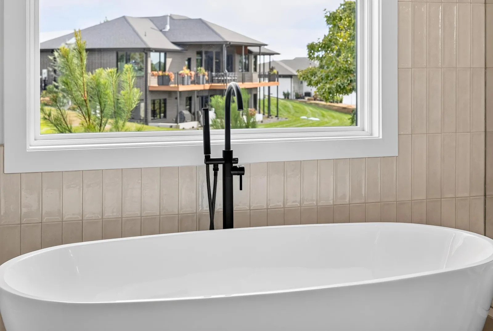 Freestanding soaking tub beneath a large picture window