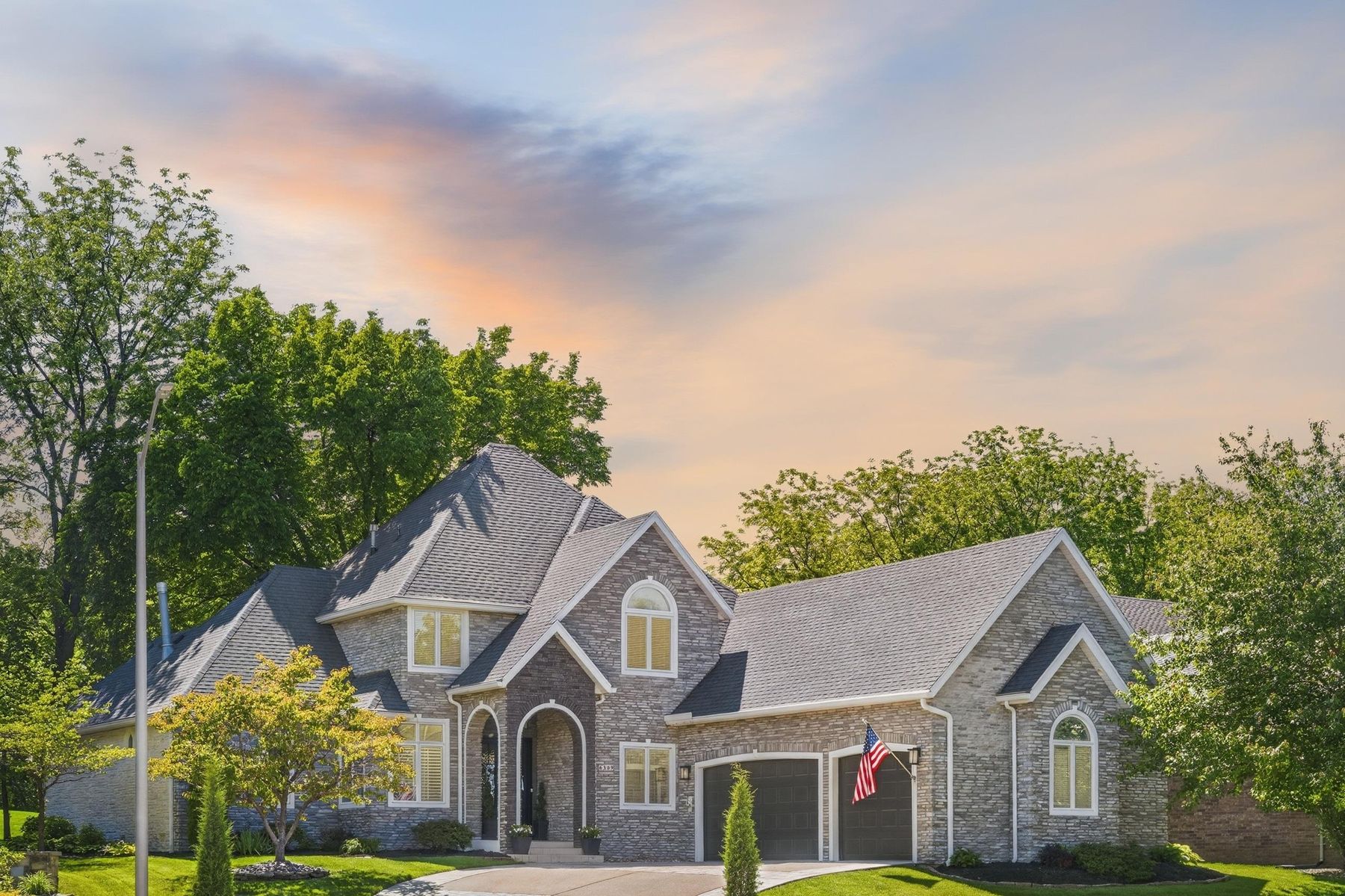 Two-story stone home under a pastel dusk sky